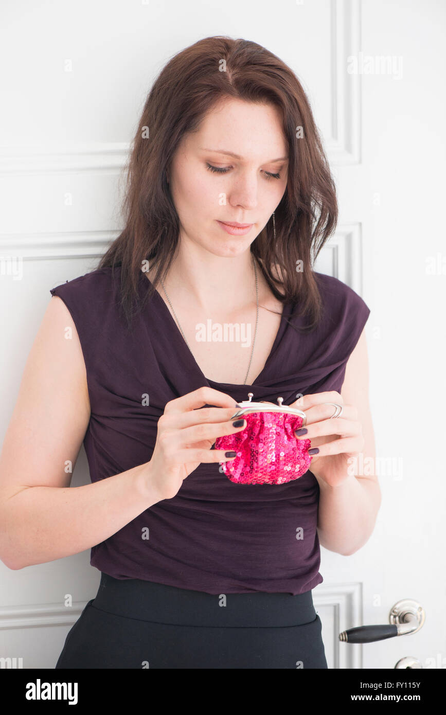 Porträt der Frau hält eine rote Geldbörse Lifestyle Bild der jungen Frau im schwarzen Kleid Konzept des Einkaufens Eigenheim-Finanzierung und Stockfoto