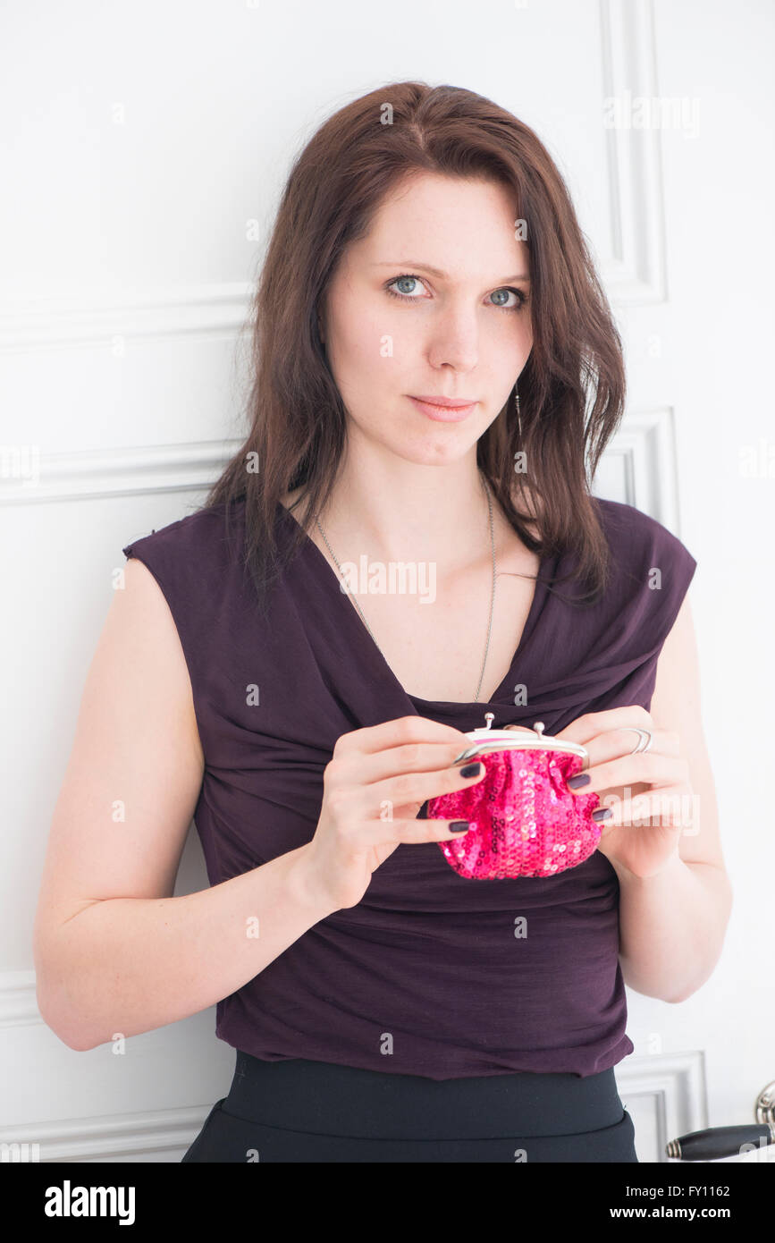 Porträt der Frau hält eine rote Geldbörse Lifestyle Bild der jungen Frau im schwarzen Kleid zeigt stolz Zuversicht und Entschlossenheit. Stockfoto