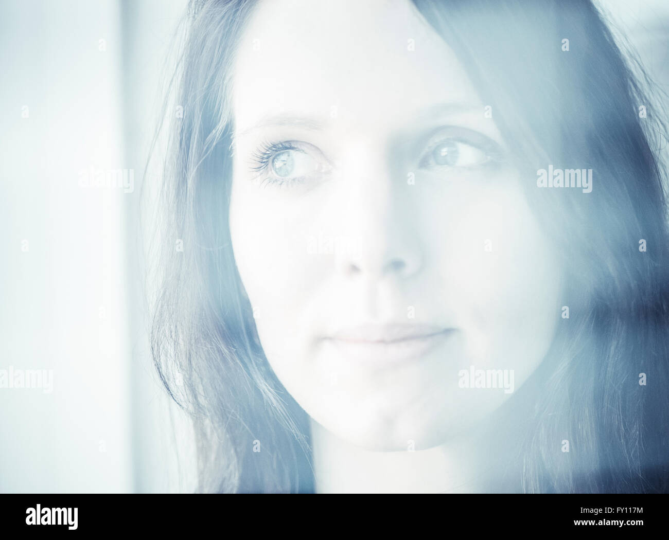 Porträt der Frau durch ein Fenster. Konzept der Traurigkeit, warten und Vorfreude. Lifestyle-Bild der Kontemplation. Stockfoto