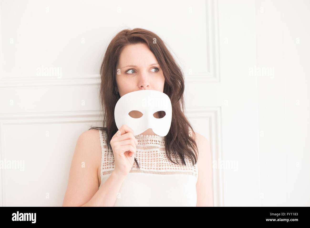 Frau halten weiße Gesichtsmaske. Konzept von Identität, Unfug und Spaß. Spielerische Lebensstil Moment. Stockfoto