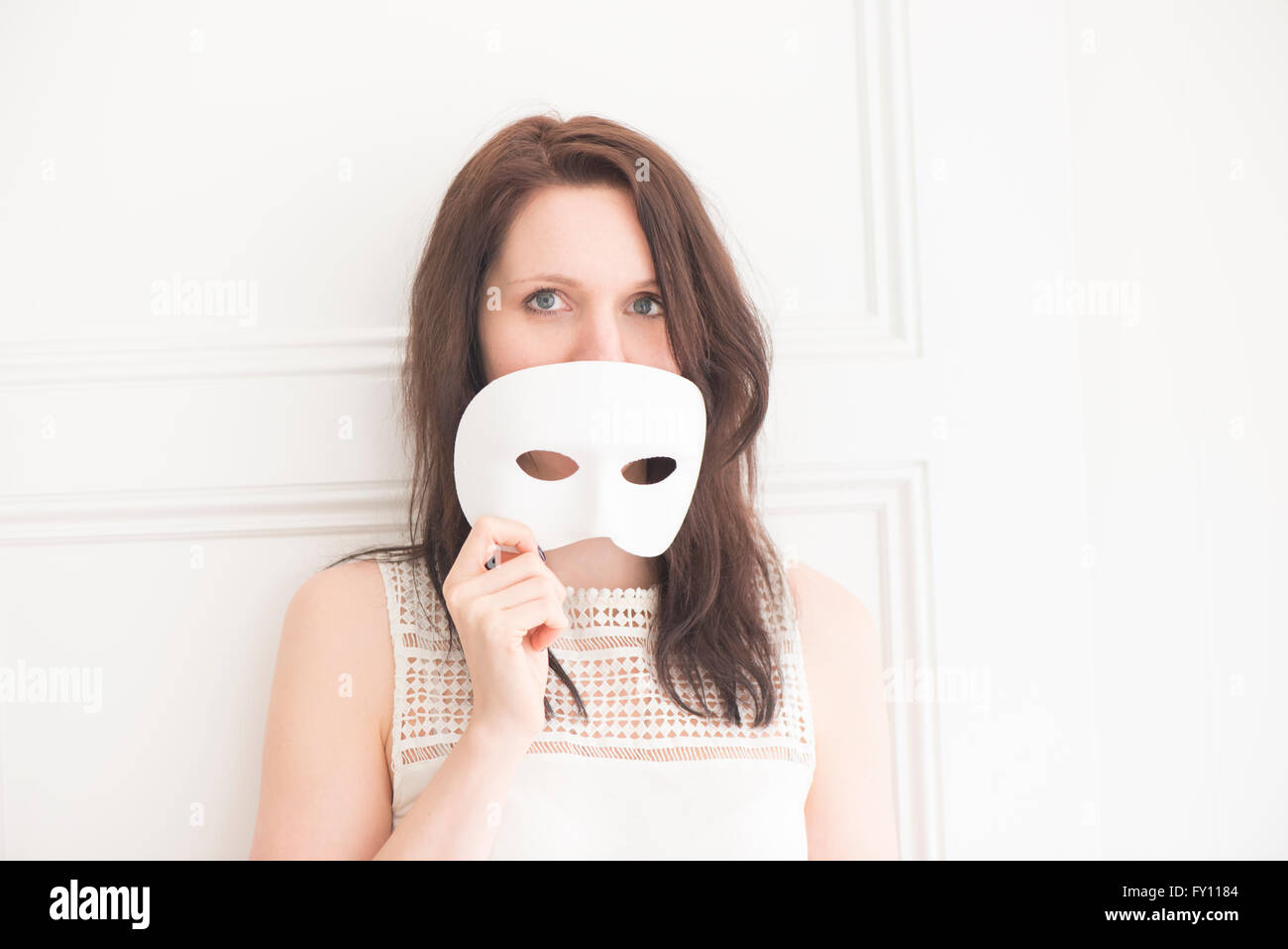 Frau halten weiße Gesichtsmaske. Konzept von Identität, Unfug und Spaß. Spielerische Lebensstil Moment. Stockfoto