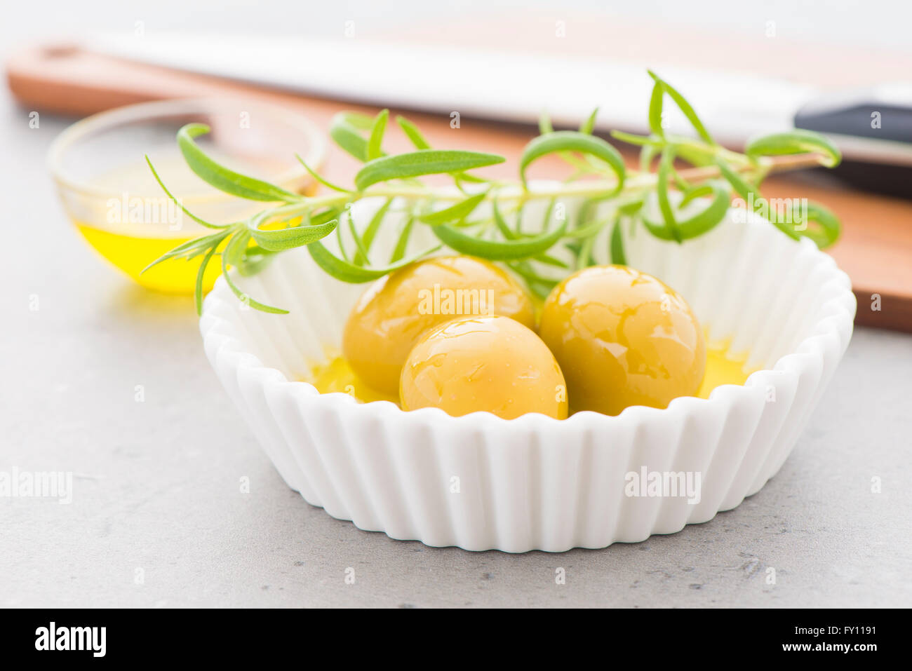 Grüne Oliven in Olivenöl und einem Zweig frischer Thymian. Still-Leben Foto von Vorspeise oder Snack. Stockfoto