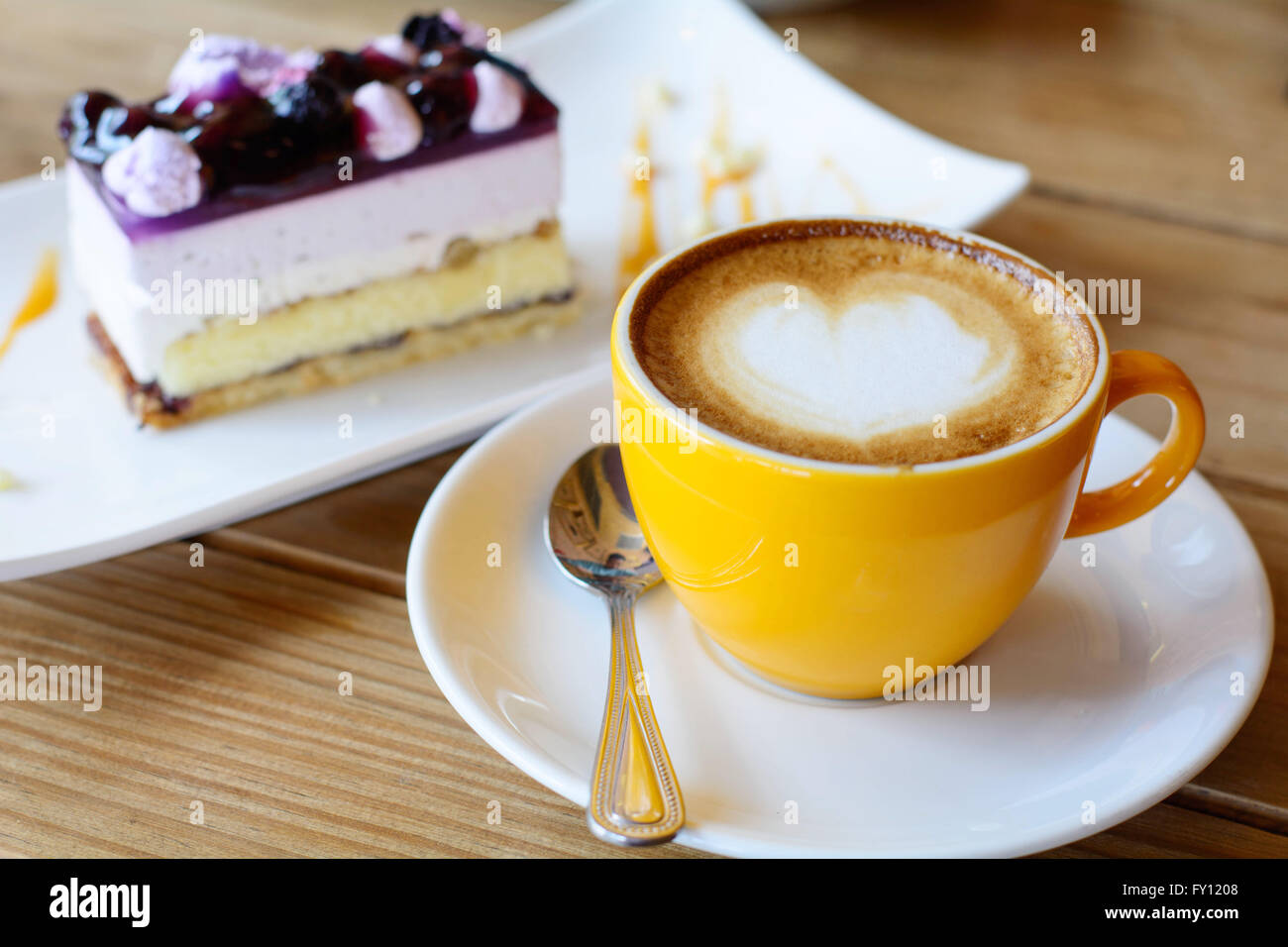 heißen Kaffee Latte Kunst und Kaffee Schaum mit Blaubeerkuchen auf Holztisch Stockfoto