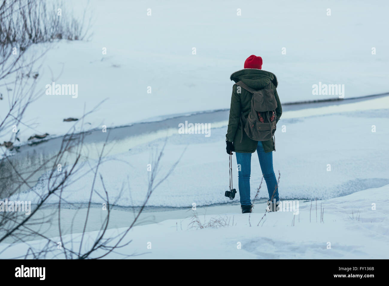 Frau mit Rucksack Kamera stehend auf Feld halten, im winter Stockfoto