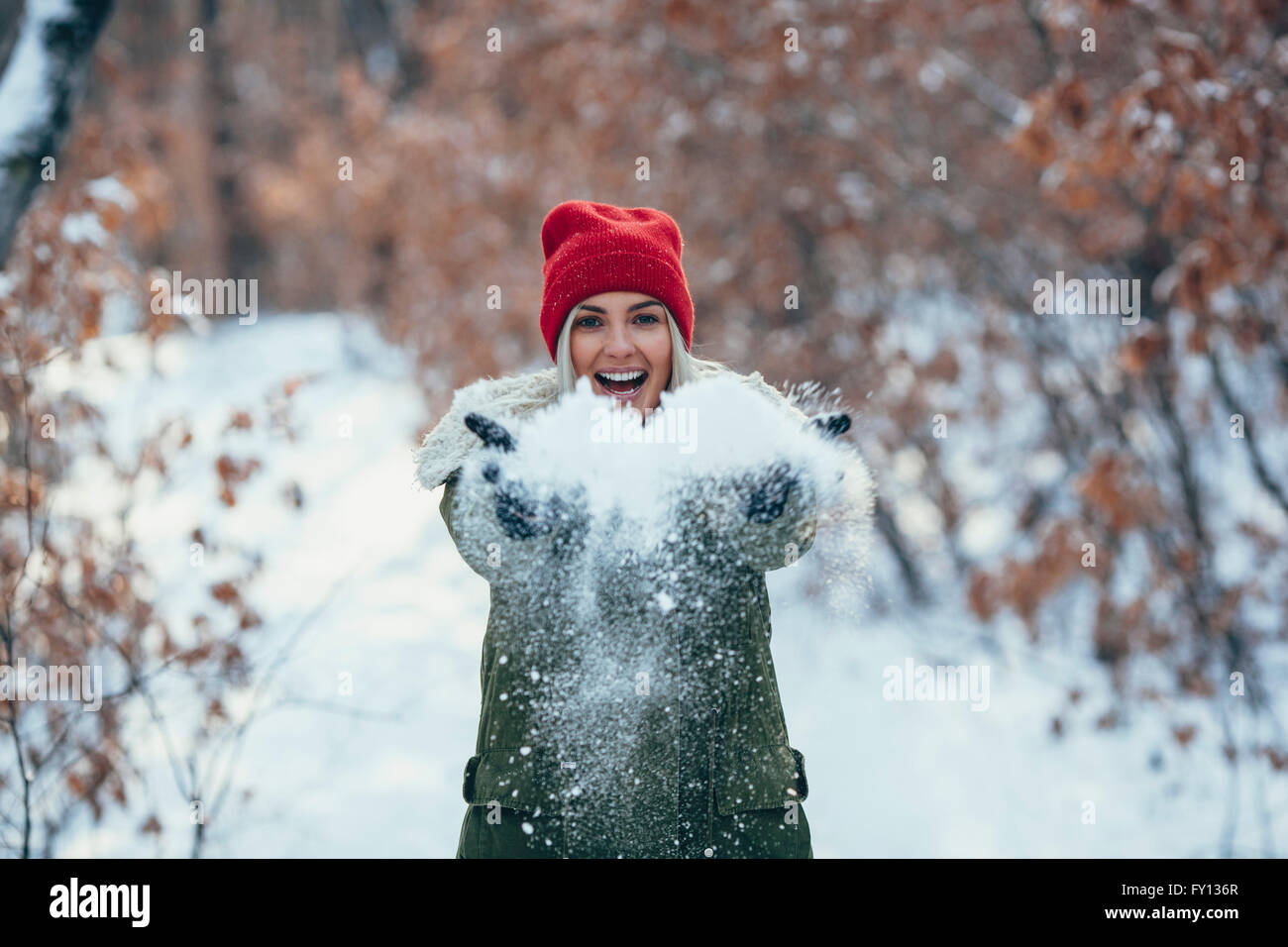 Porträt der glückliche junge Frau spielt mit Schnee Stockfoto