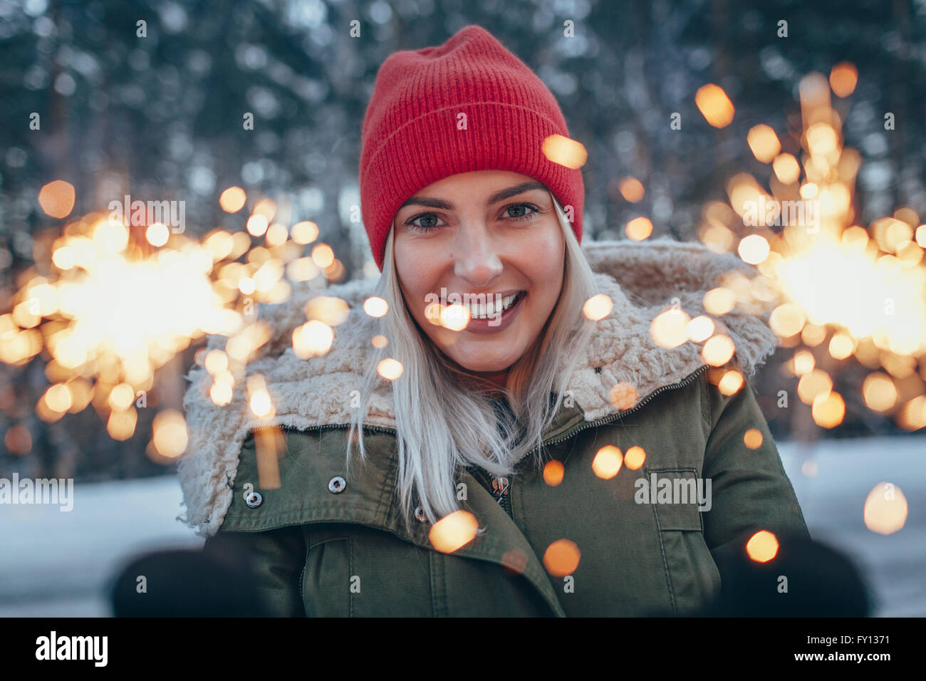 Porträt von lächelnden Frau Holding Wunderkerzen im winter Stockfoto