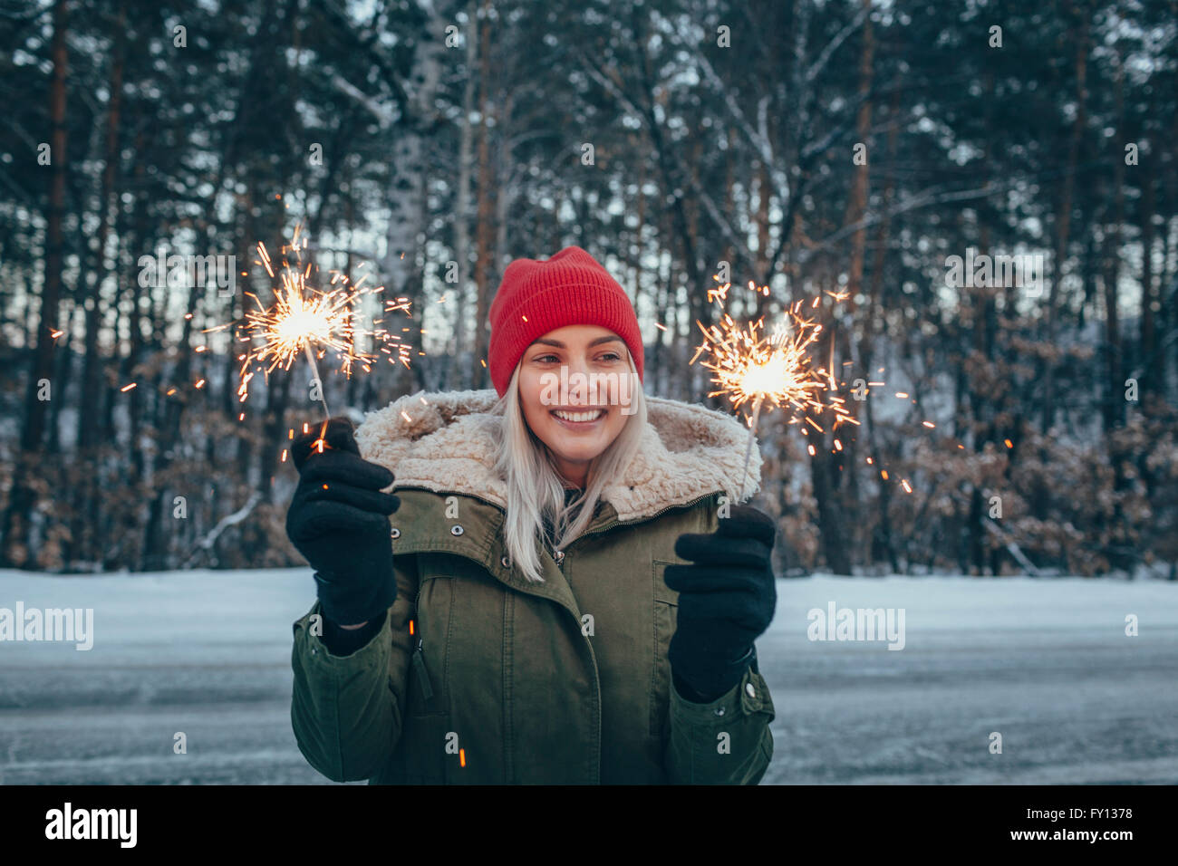 Lächelnde Frau mit Wunderkerzen im winter Stockfoto