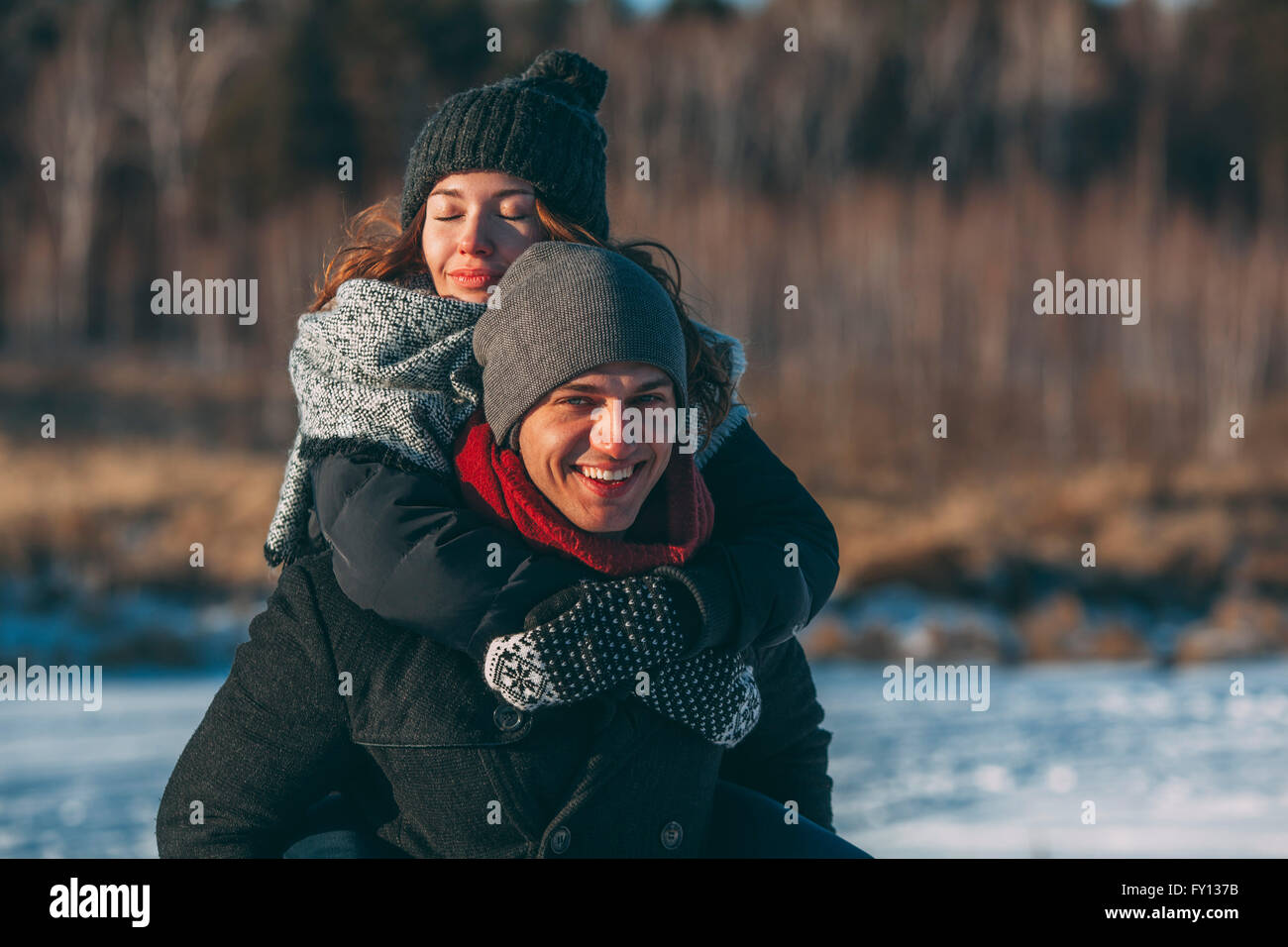 Porträt von glücklicher Mann Frau Huckepack Fahrt einzuräumen, im winter Stockfoto