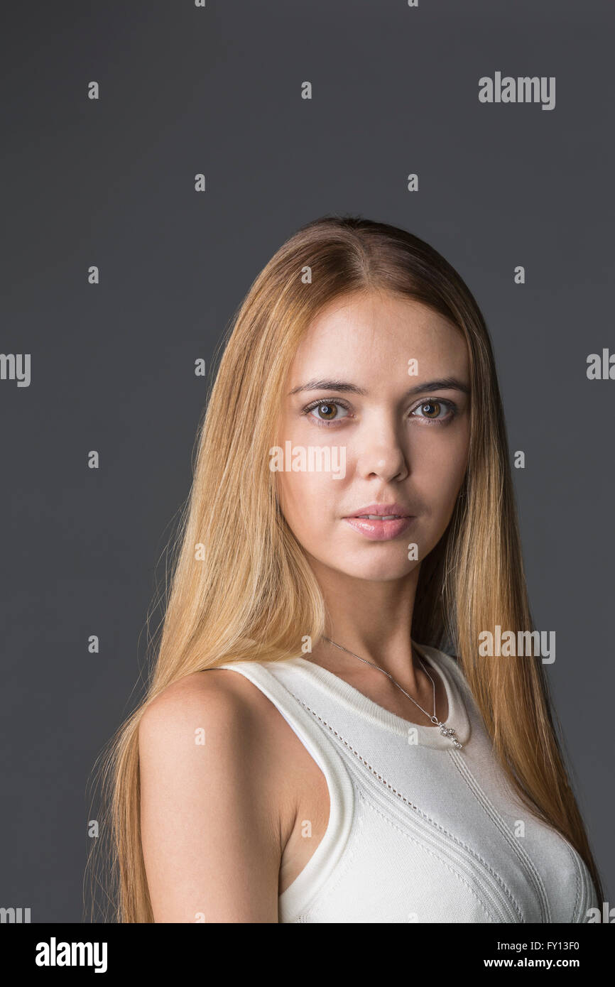 Porträt der selbstbewusste Frau mit langen Haaren vor grauem Hintergrund Stockfoto