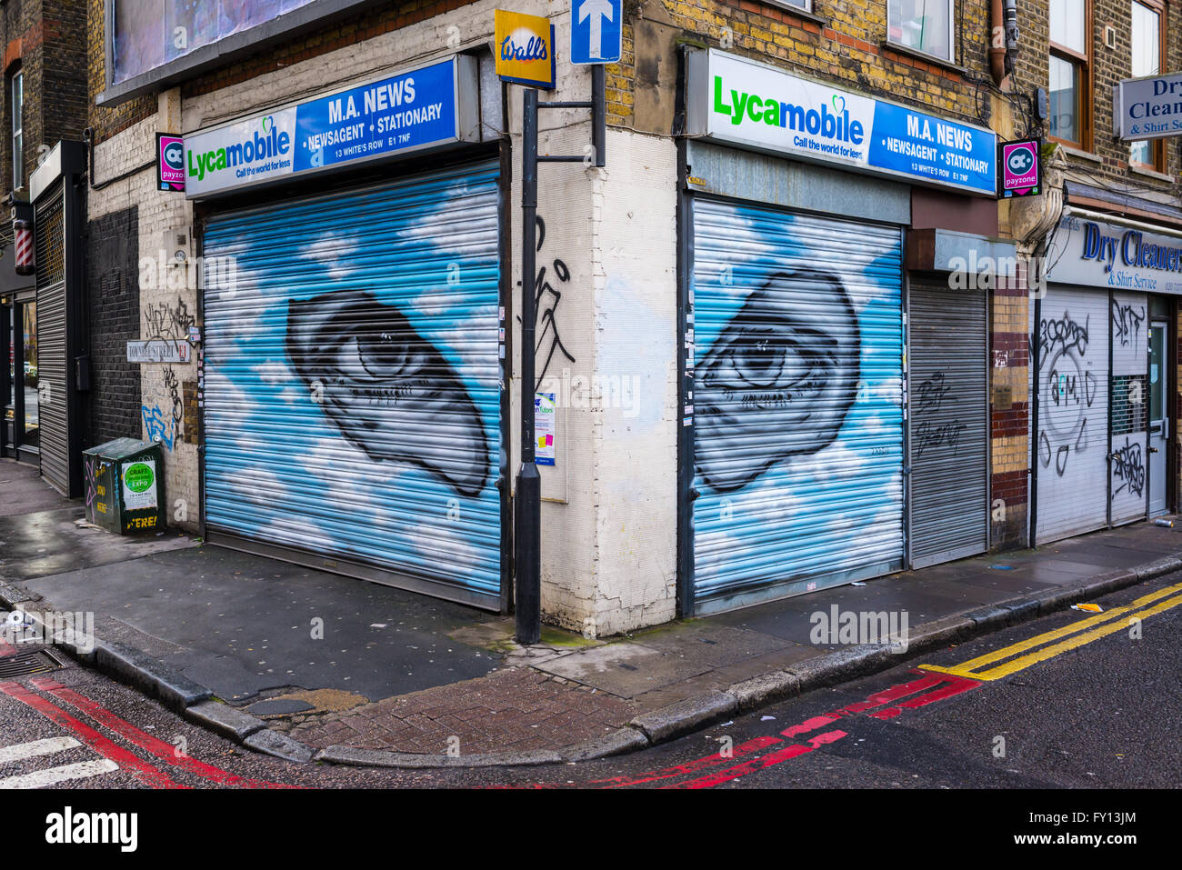 Kiosk-Shop mit Fensterläden nach unten und Graffiti repräsentieren zwei Augen starrte durch kleine Löcher im blauen Himmel geschlossen Stockfoto