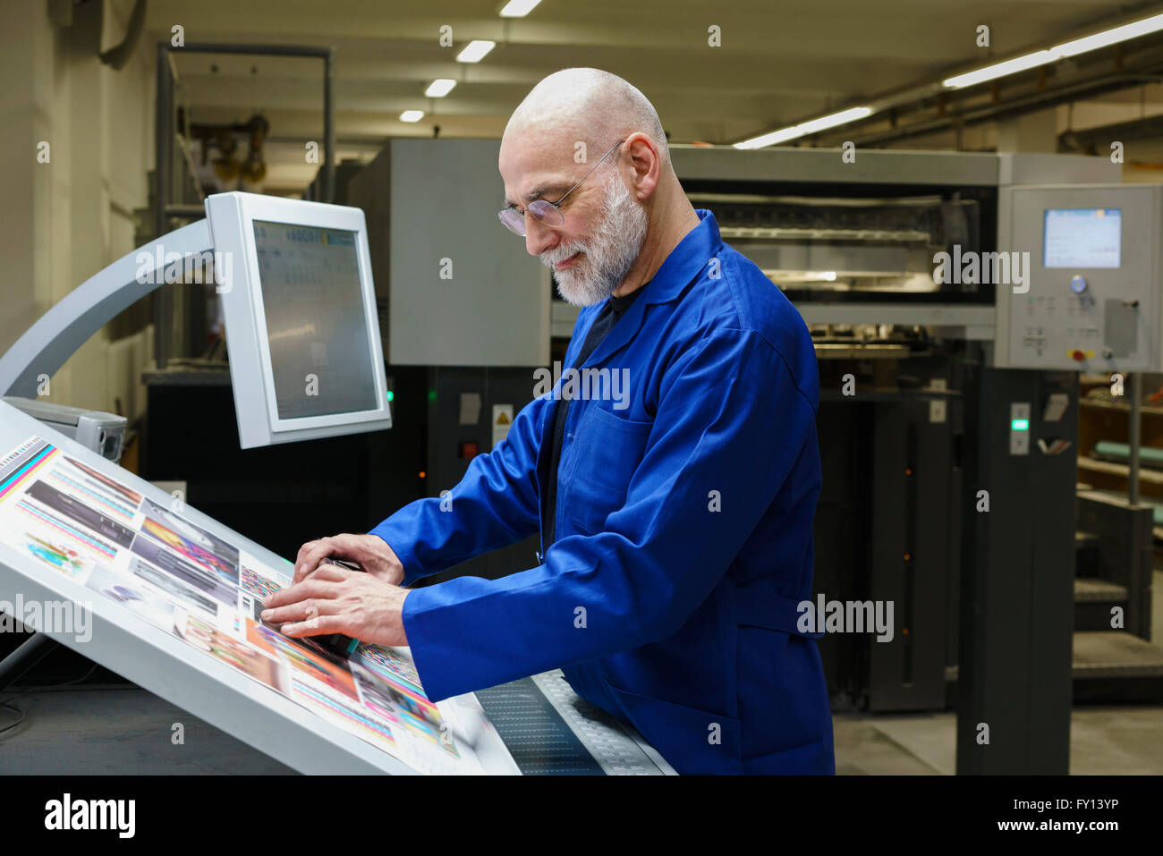 Reifer Mann tun Qualitätsüberprüfung des Ausdrucks mit Scanner an Druckmaschine Stockfoto