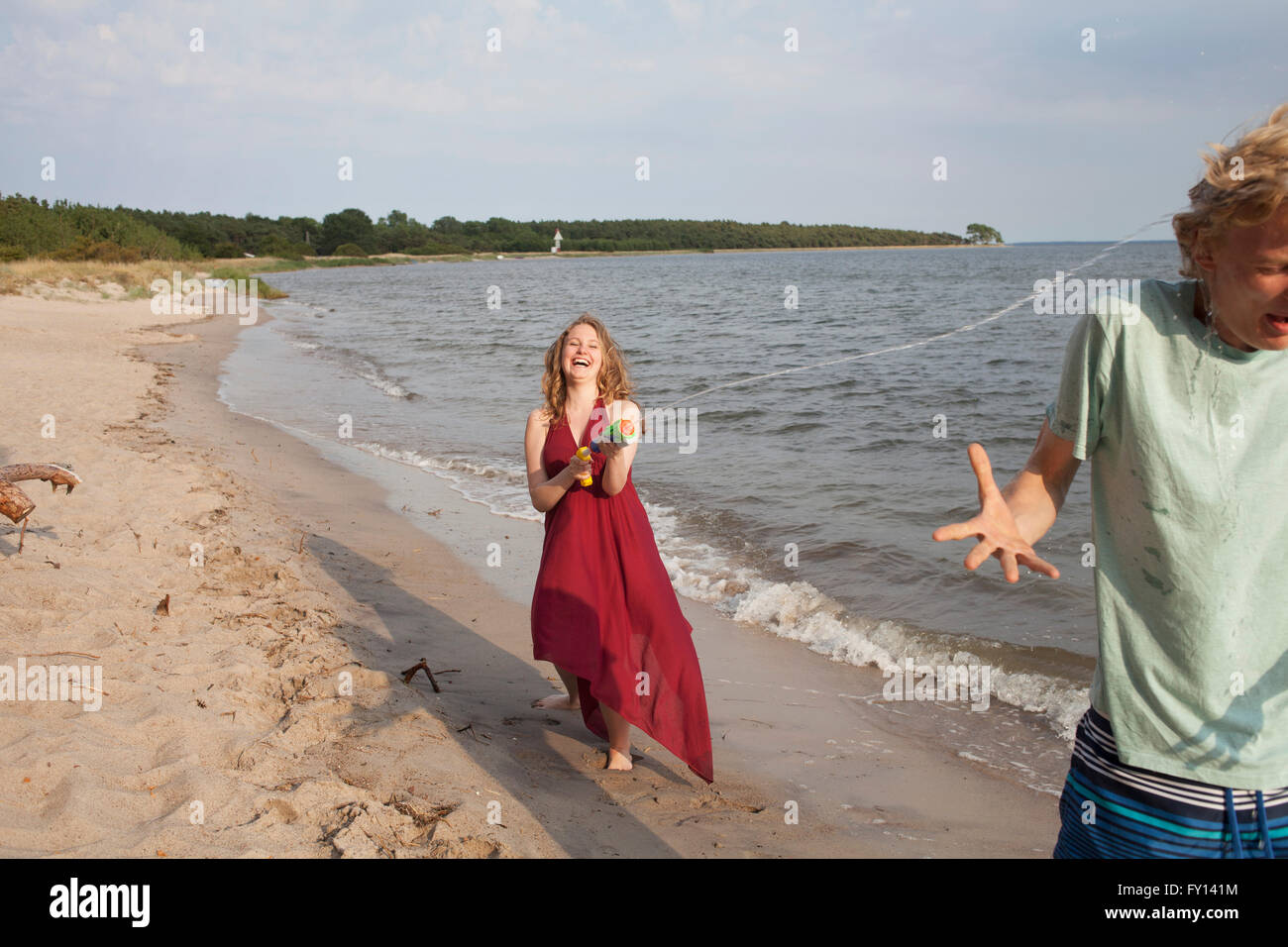 Frau Freund mit Spritzpistole am Strand Wasser Aufsprühen Stockfoto
