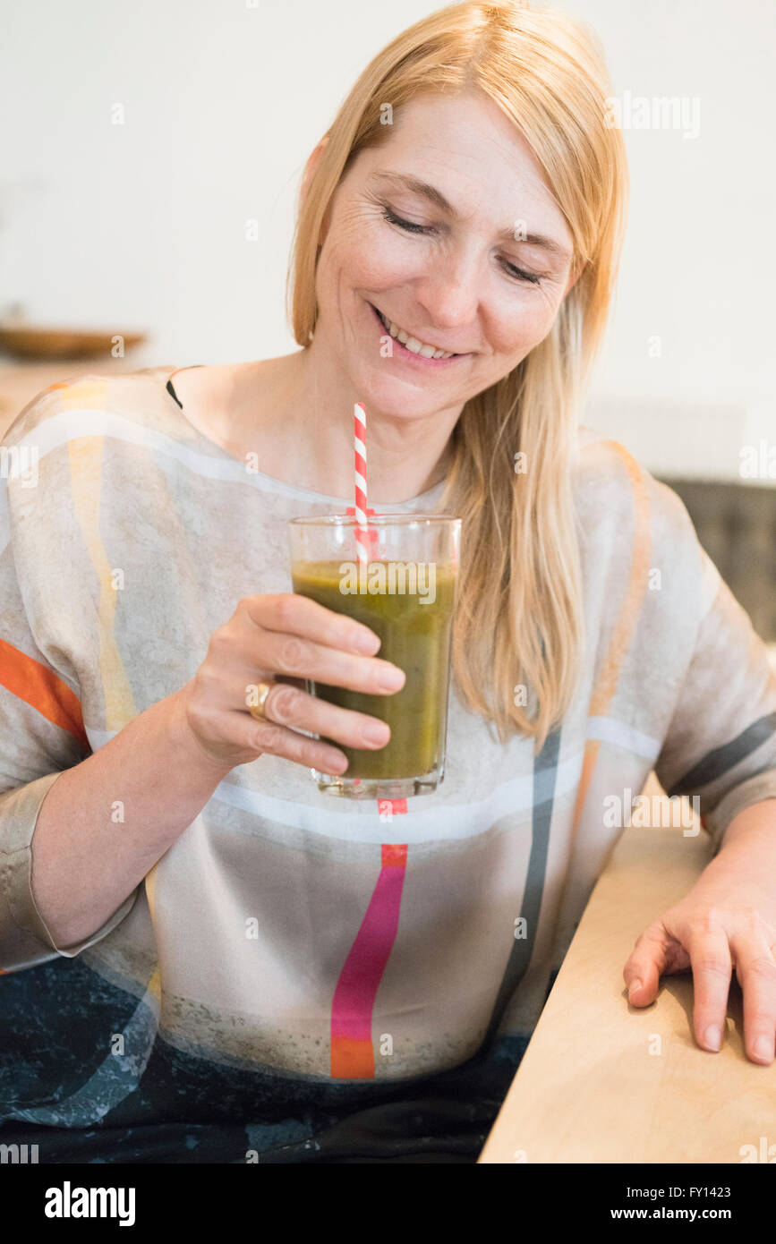 Glücklich Reife Frau hält einen Smoothie in ein Glas zu Hause Stockfoto