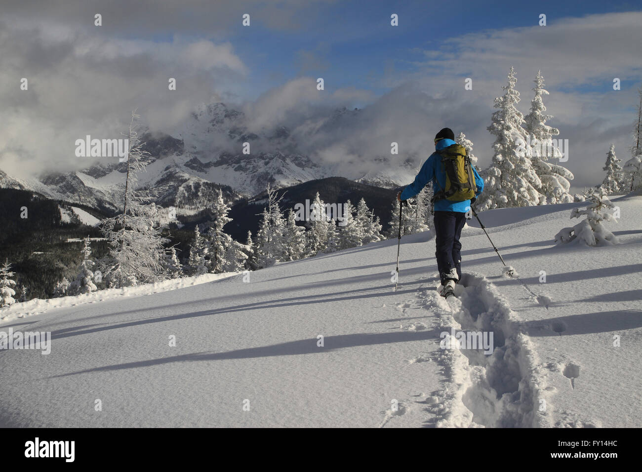 Mann trägt warme Kleidung, die zu Fuß auf schneebedeckten Feld gegen Berge Stockfoto