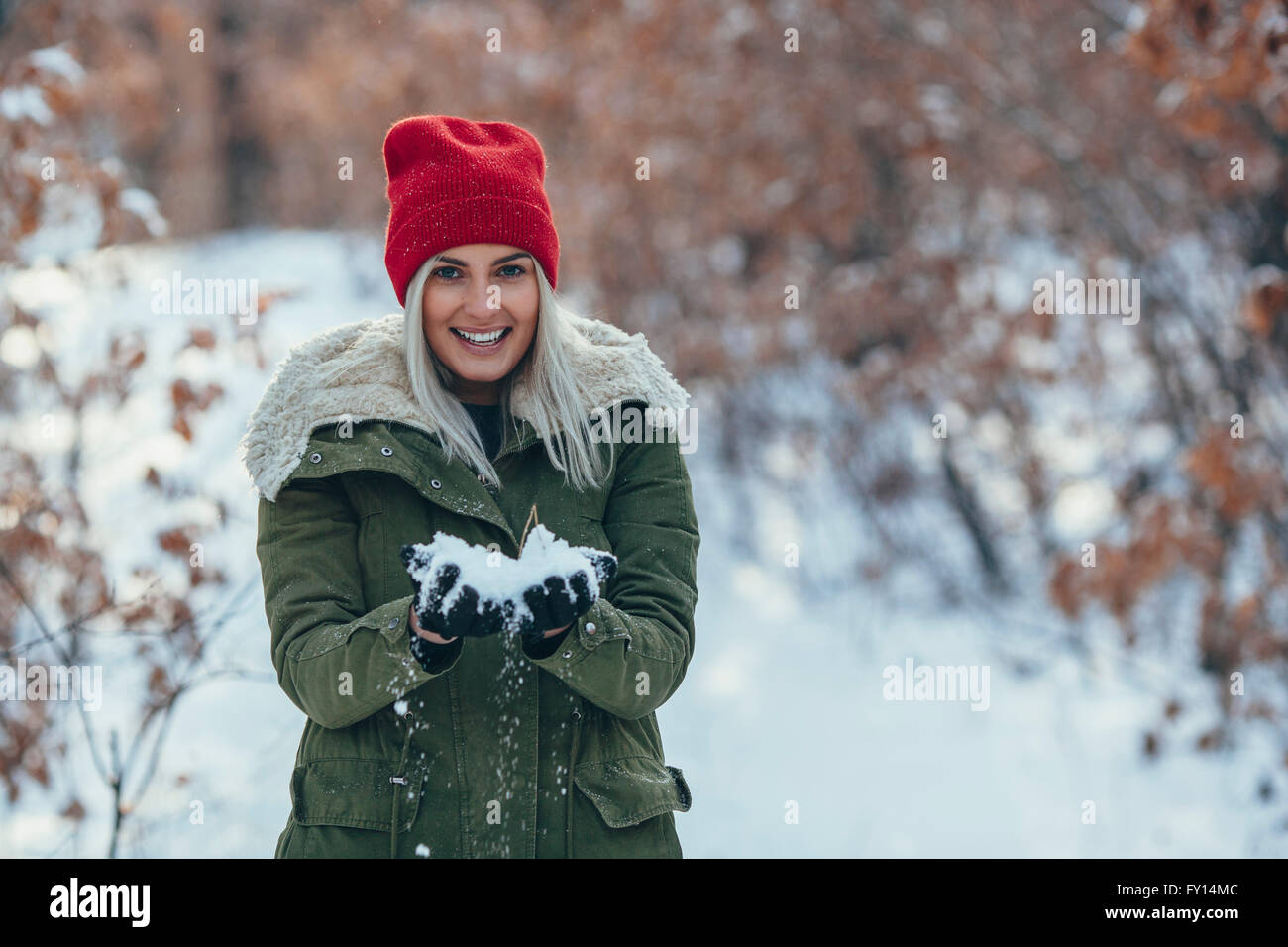 Porträt der lächelnde junge Frau halten Schnee auf Feld Stockfoto