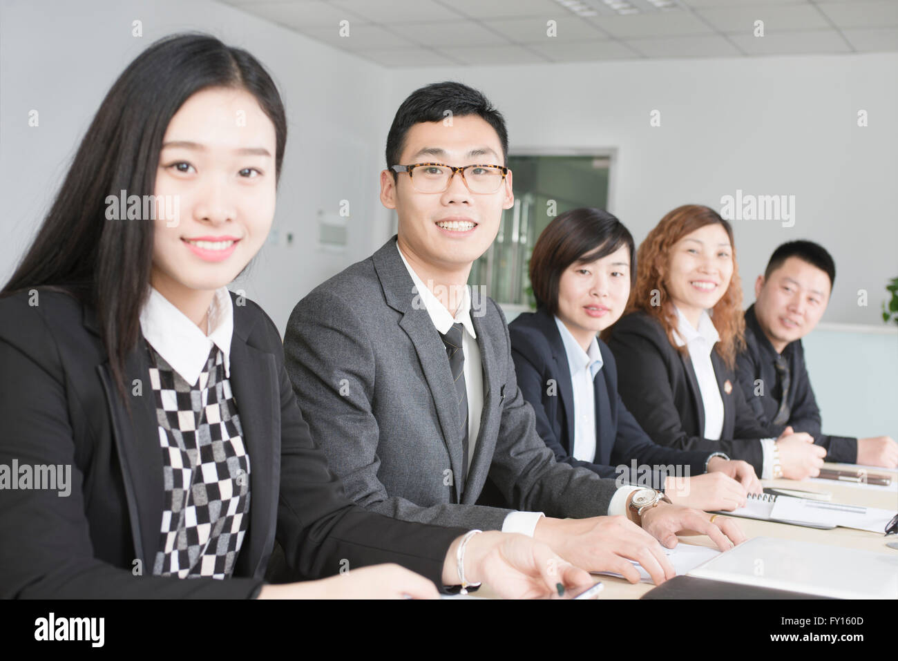 Unternehmensgruppe, die ethnischen Vielfalt in einer Sitzung lächelnd in die Kamera zeigen Stockfoto