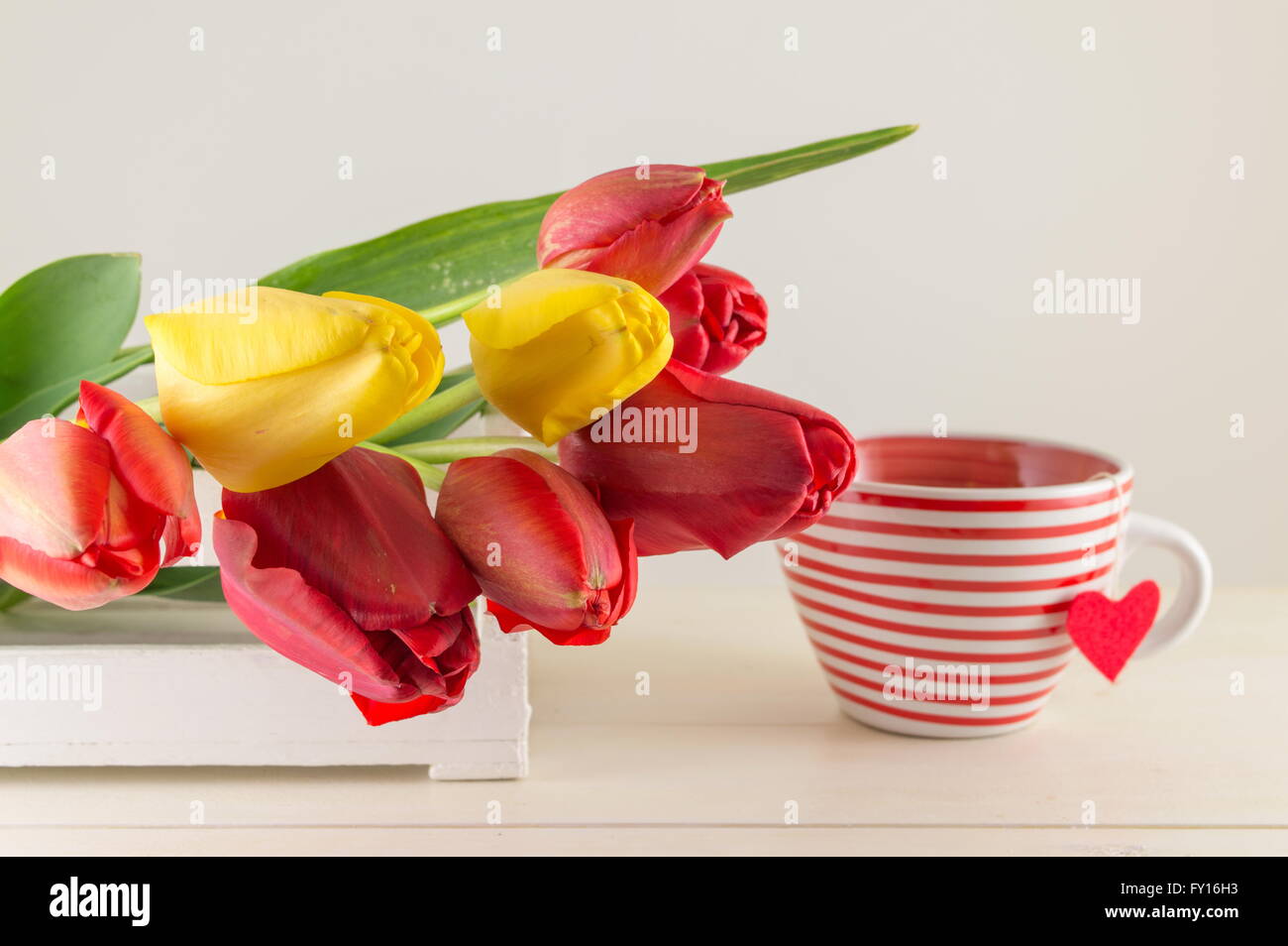 Rote und gelbe Tulpen auf einem Holztisch Stockfoto