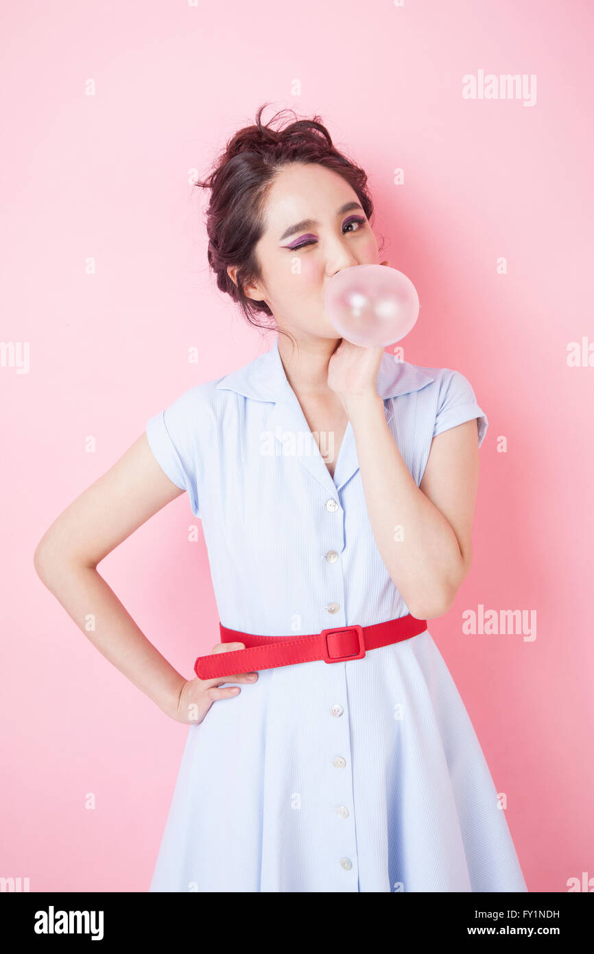 Junge lächelnde Frau im Retro-Stil, die Seifenblase Gum zwinkert, starrte auf Vorderseite Stockfoto