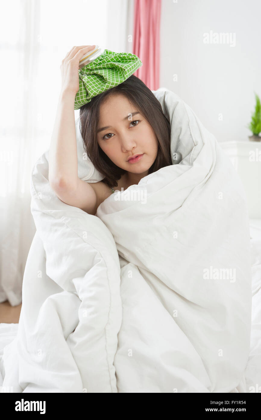 Porträt der jungen Frau in eine Decke mit Eisbeutel auf dem Kopf Stockfoto