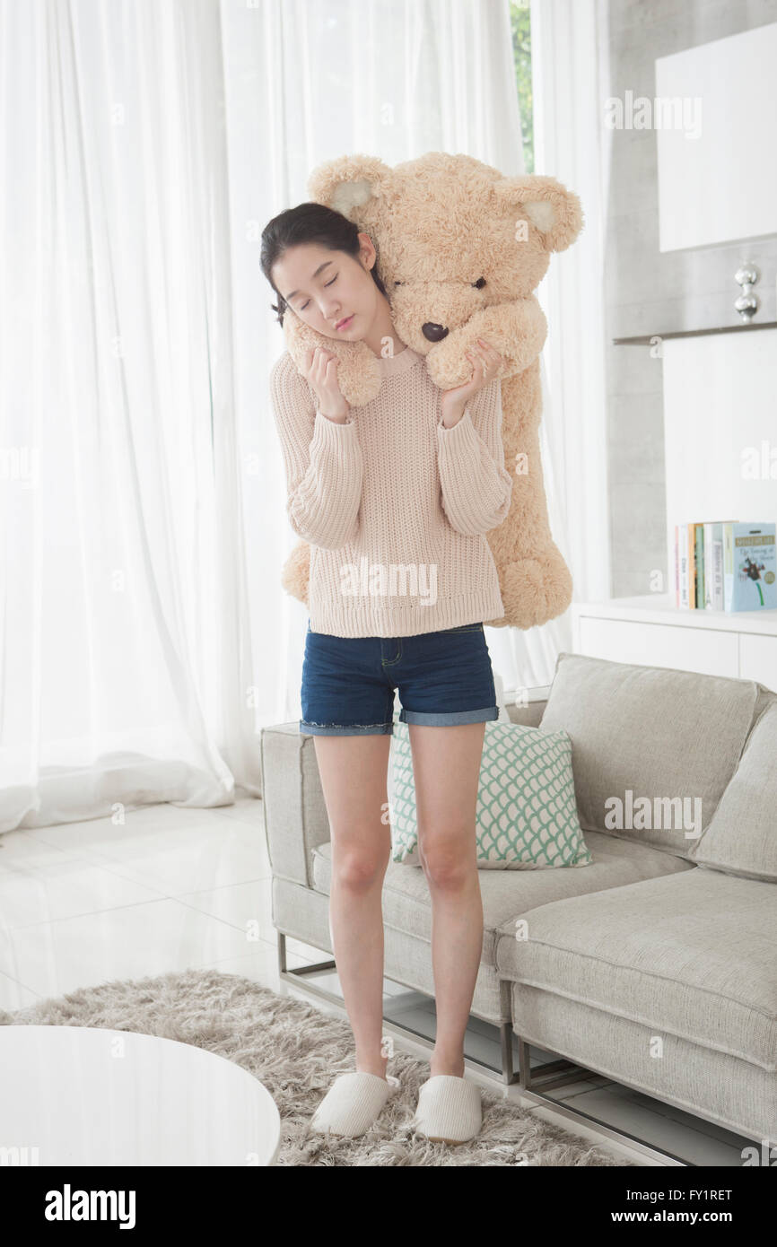 Junge Frau mit einem großen Teddybären auf dem Rücken, ihre Augen zu schließen Stockfoto