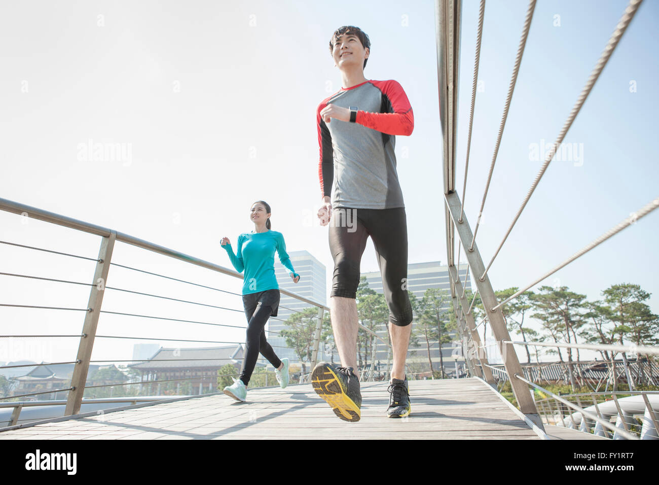 Niedrigen Winkel Blick auf junge lächelnde paar Joggen im park Stockfoto