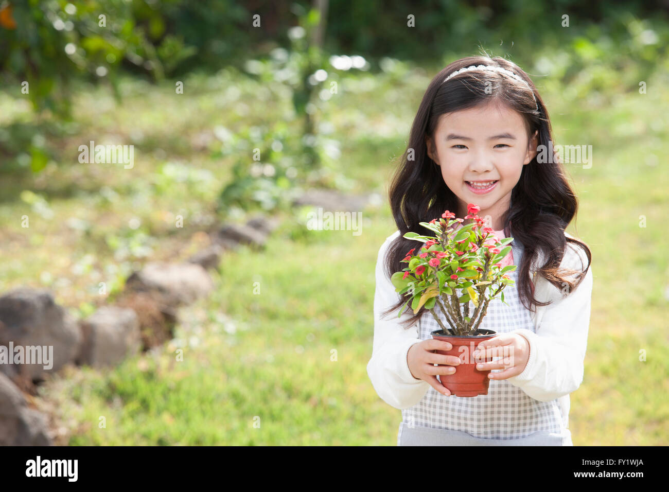 Mädchen hält einen Topf Pflanzen nach vorne und lächelte den Garten in Jeju Stockfoto