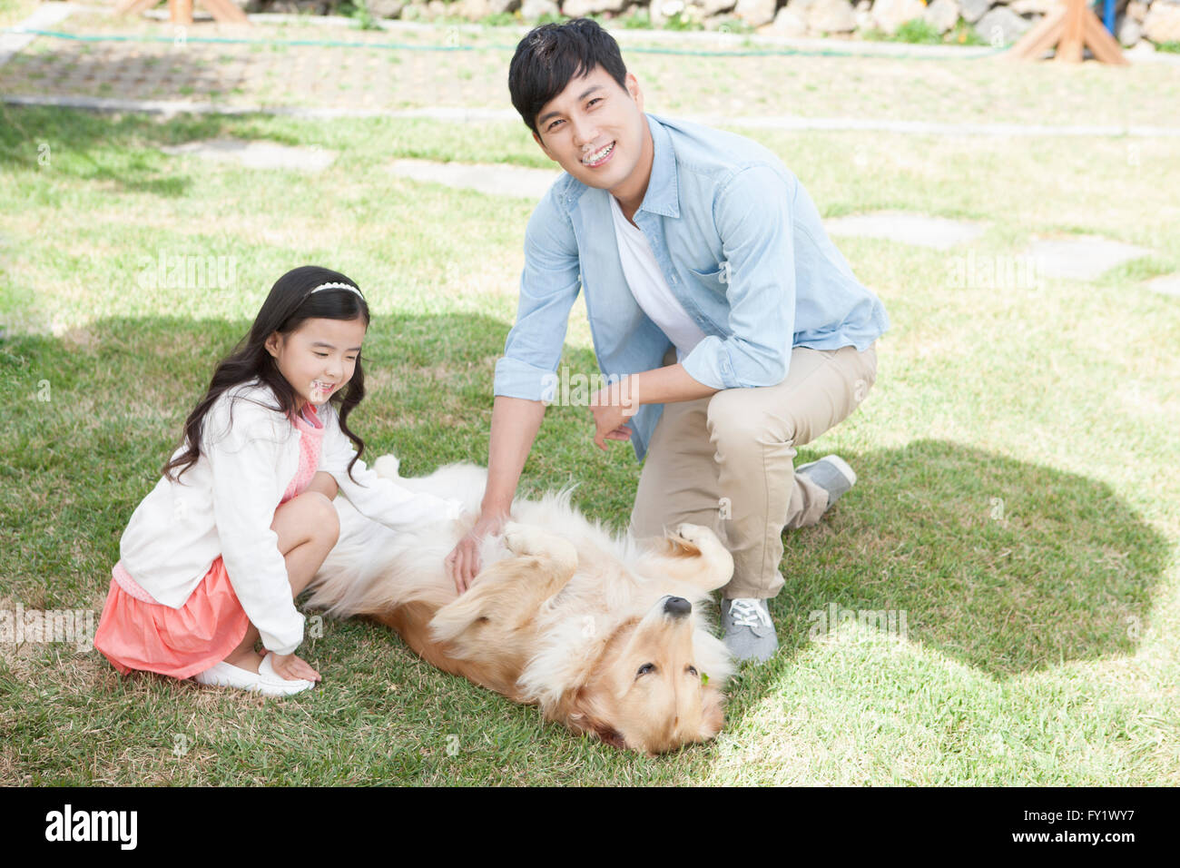 Tochter und Vater Berühren eines Hundes liegen auf einem Hof die ländliche Leben darstellen Stockfoto