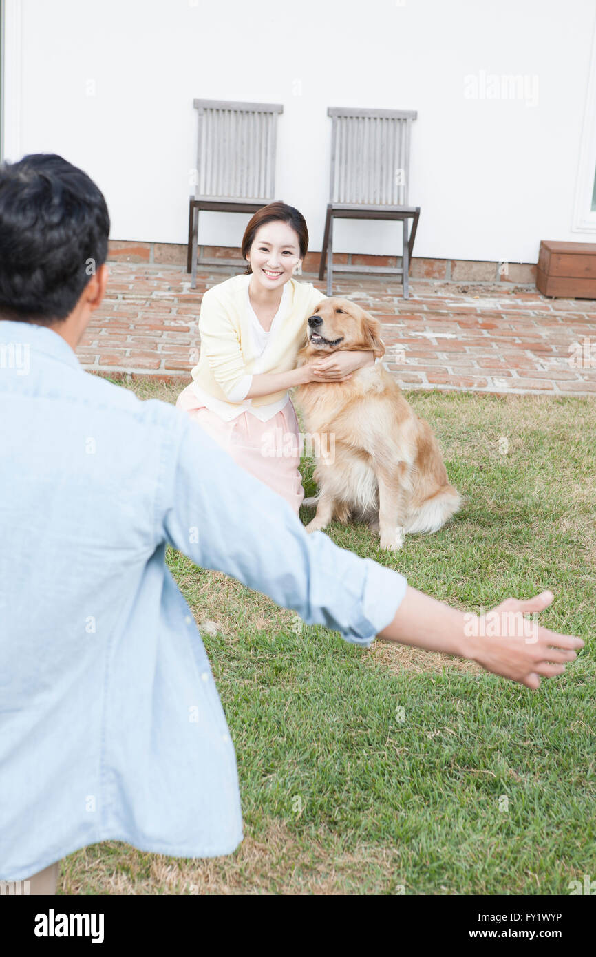Erscheinung eines Menschen seine Arme in Richtung Frau zu öffnen, mit einem Hund auf dem Hof zurück Stockfoto