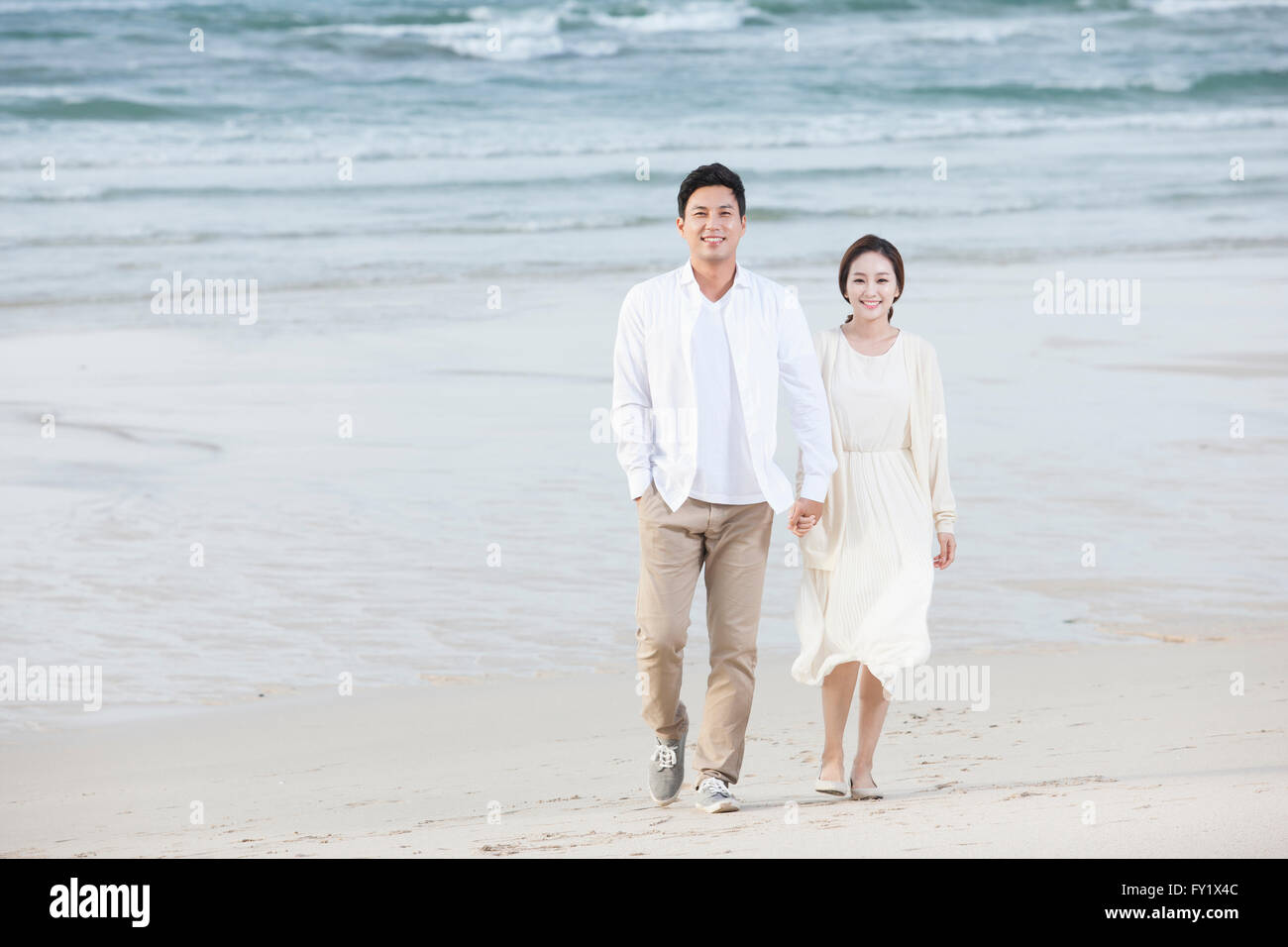 Paar am Strand hand in hand gehen Stockfoto