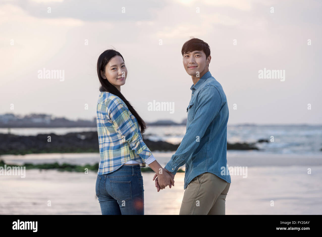 Paar Hand in hand im Rückblick mit einem Lächeln am Strand Stockfoto