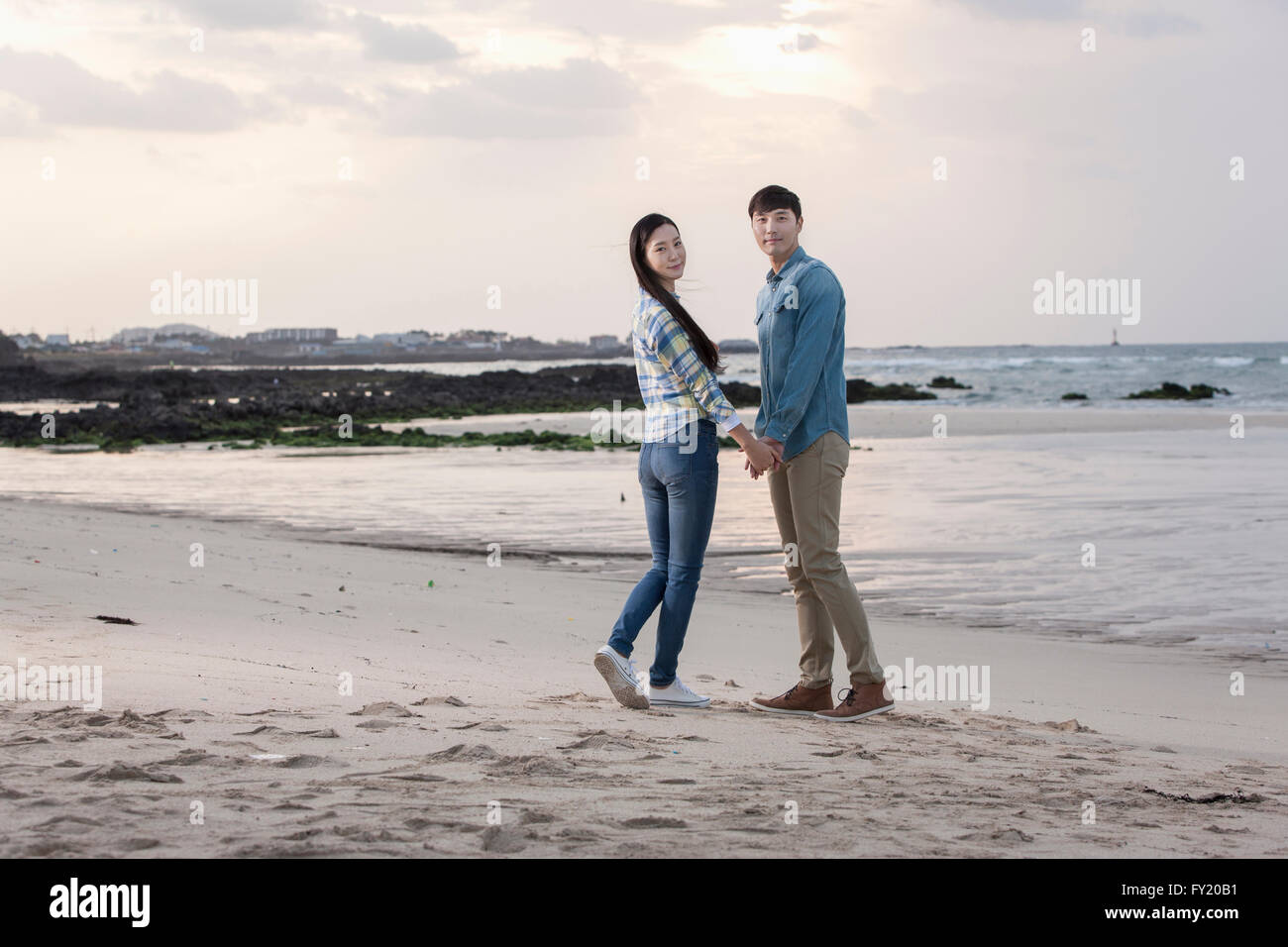 Paar stehen hand in hand und mit einem Lächeln am Strand im Rückblick Stockfoto
