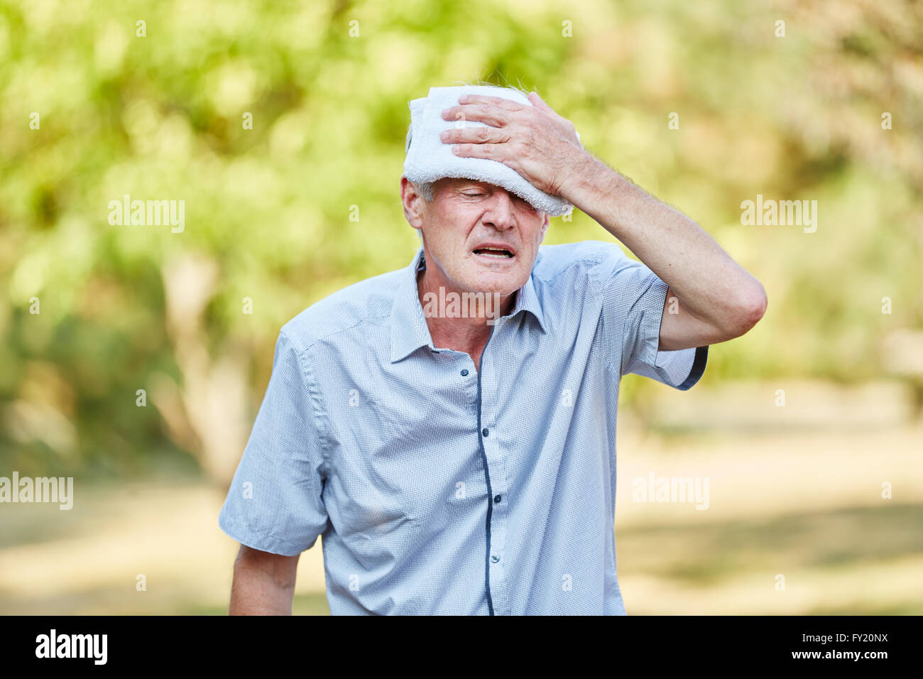 Ältere Mann mit schlechter Zirkulation kühlt den Kopf mit einem feuchten Tuch Stockfoto