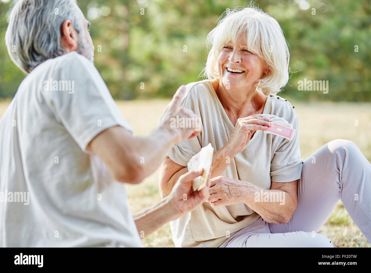 Älteres Paar Spaß haben und spielen ein Kartenspiel im Sommer in der Natur Stockfoto