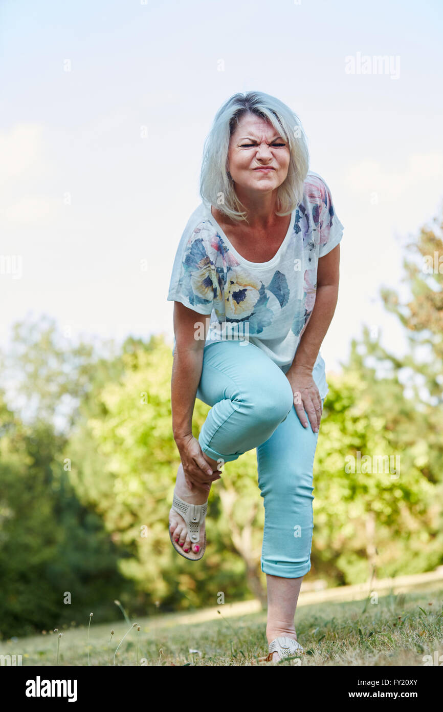 Alte Frau mit verstauchtem Fuß hat Schmerzen in der Natur Stockfoto