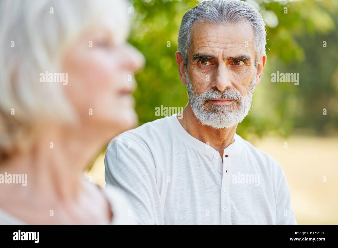 Alter Mann starrte nachdenklich auf eine Frau im Sommer in der Natur Stockfoto