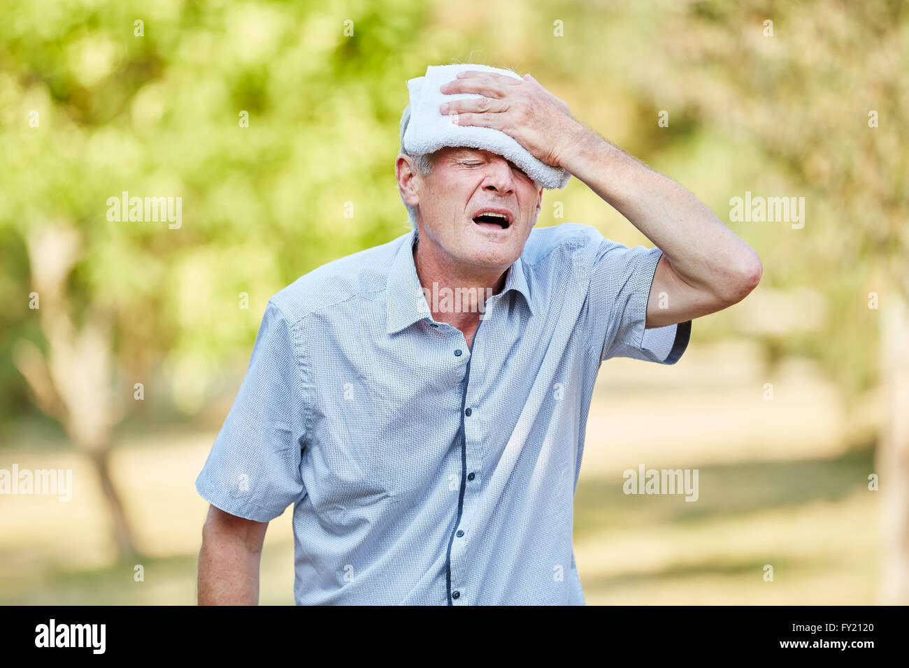Senior Ohnmacht Mann seinen Kopf mit einem feuchten Tuch abkühlen Stockfoto