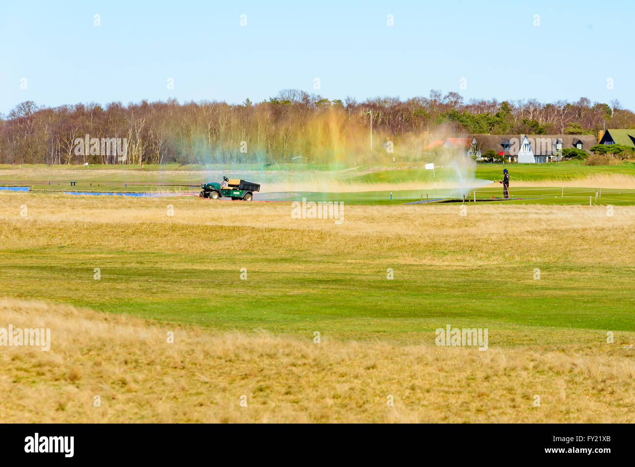 Skanor, Schweden - 11. April 2016: Männliche Arbeiter auf dem Golfplatz Bewässerung ist aber der Wasserschlauch ist undicht und verbreiten Sie Wasser in Stockfoto