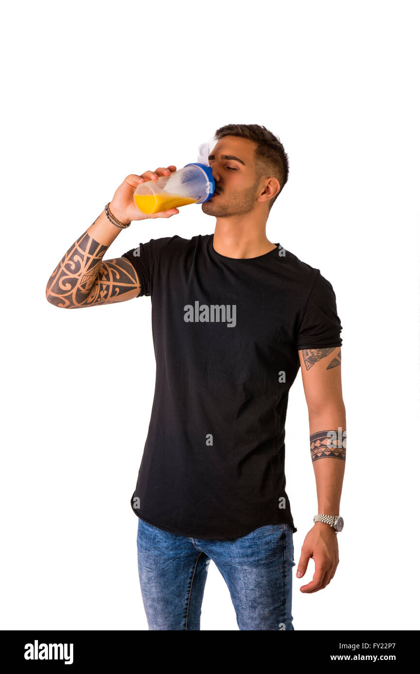 Attraktive tätowierte junge Mann halten und aus Protein Shaker Flasche trinken. Isoliert auf weiss Stockfoto