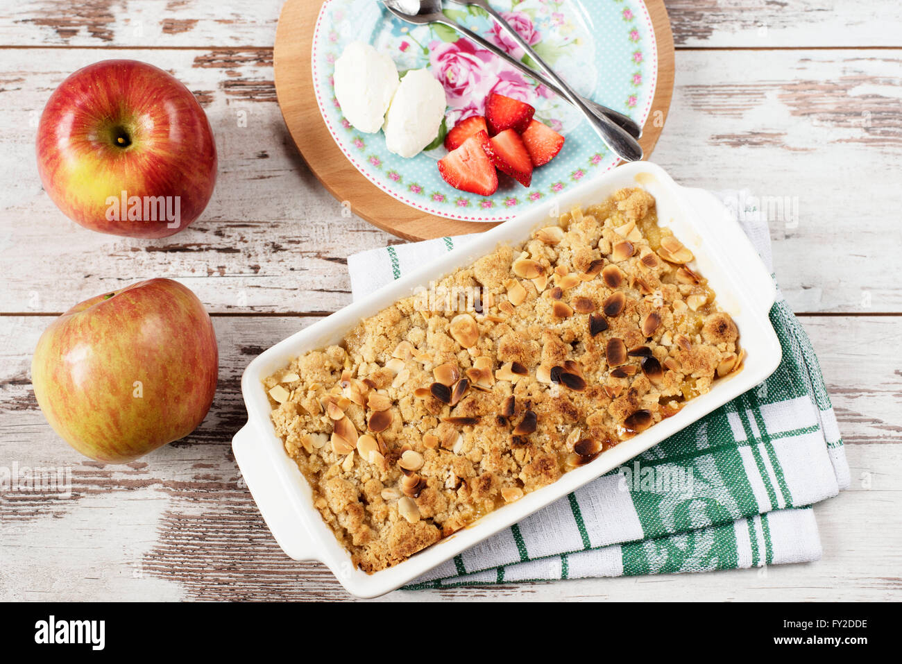 Apple crumble Dessert mit Erdbeeren und Vanillecreme auf rustikalen hölzernen Hintergrund Stockfoto