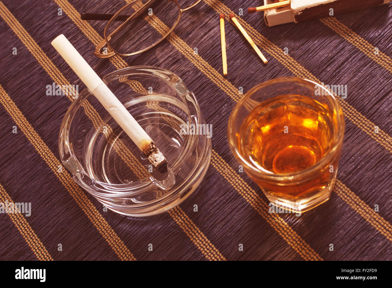 Glas Whisky und Zigarette im Aschenbecher. Stockfoto