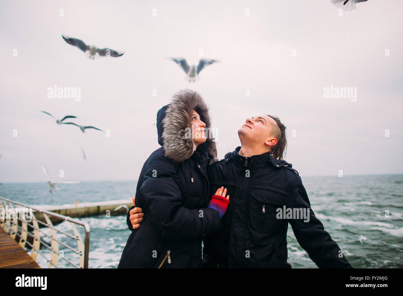 Liebhaber, die Hand in Hand auf der Pier und Möwen leise im Hintergrund. Romantische Hochzeitsreise im Winter Stockfoto