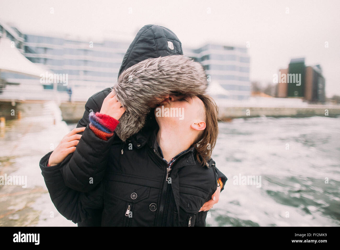 Urbane Mode glückliche Paar leidenschaftlich küssen in einem sonnigen Wintertag. Schöne romantische Momente. Stadtbild auf Hintergrund Stockfoto