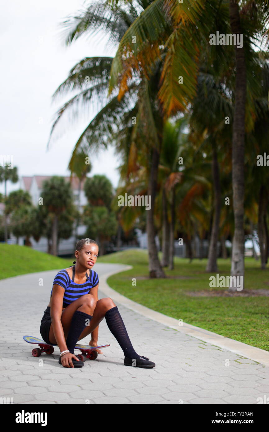 Frau sitzt auf einem Skateboard im park Stockfoto