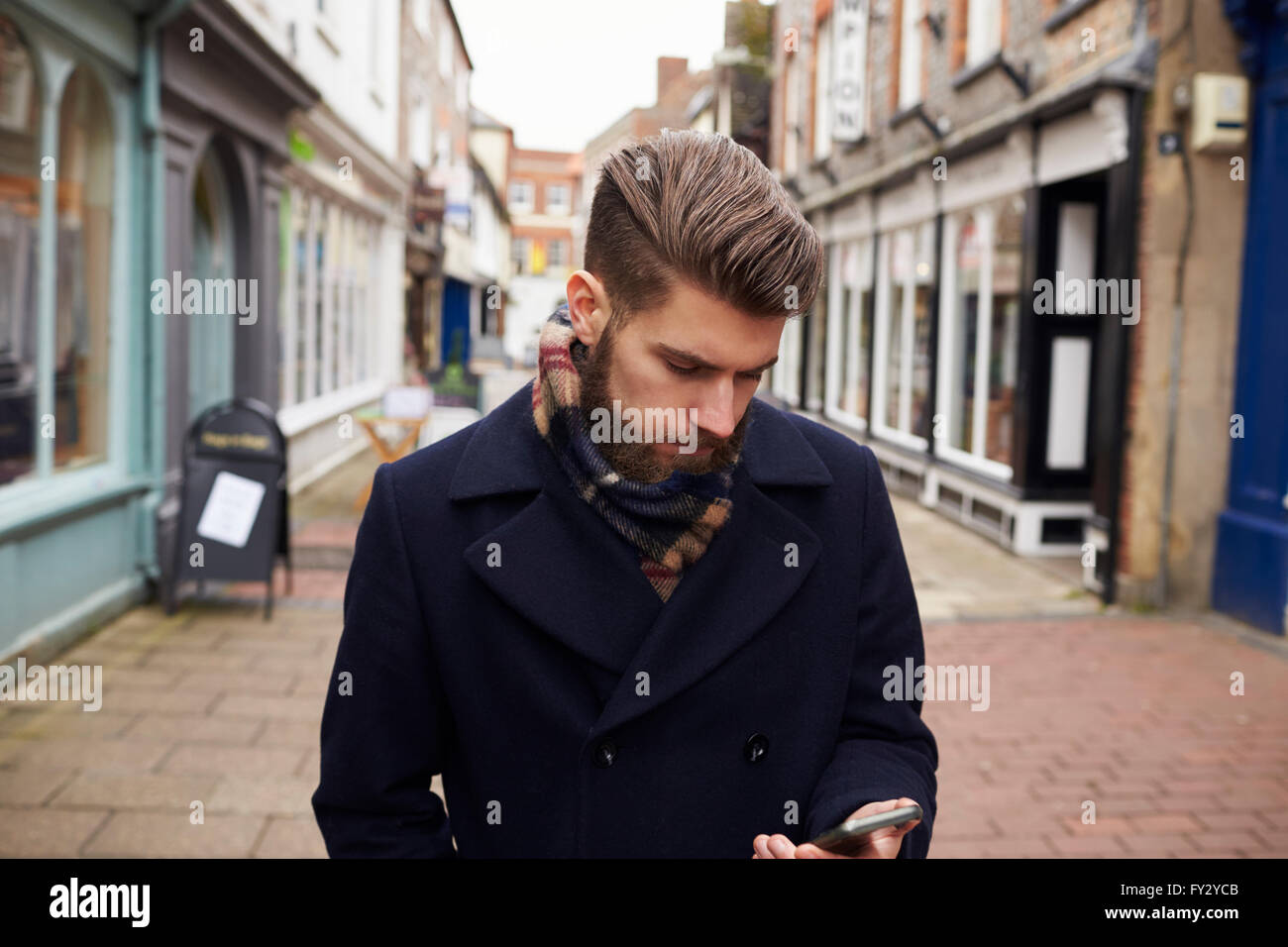 Mann zu Fuß hinunter Urban Street Check SMS auf Handy Stockfoto