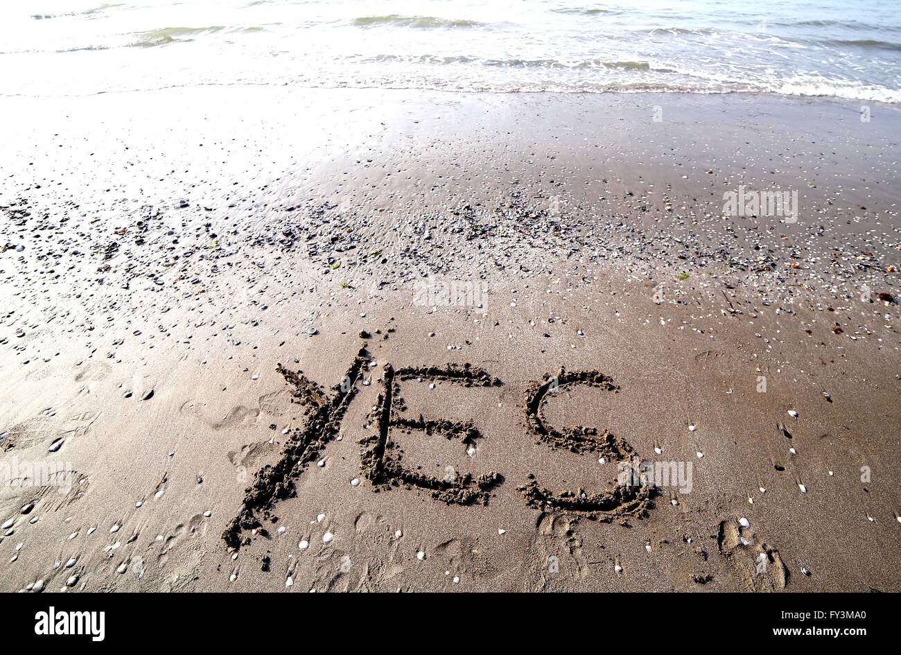 Große Schrift auf dem Sand des Meeres mit dem Wort ja Stockfoto