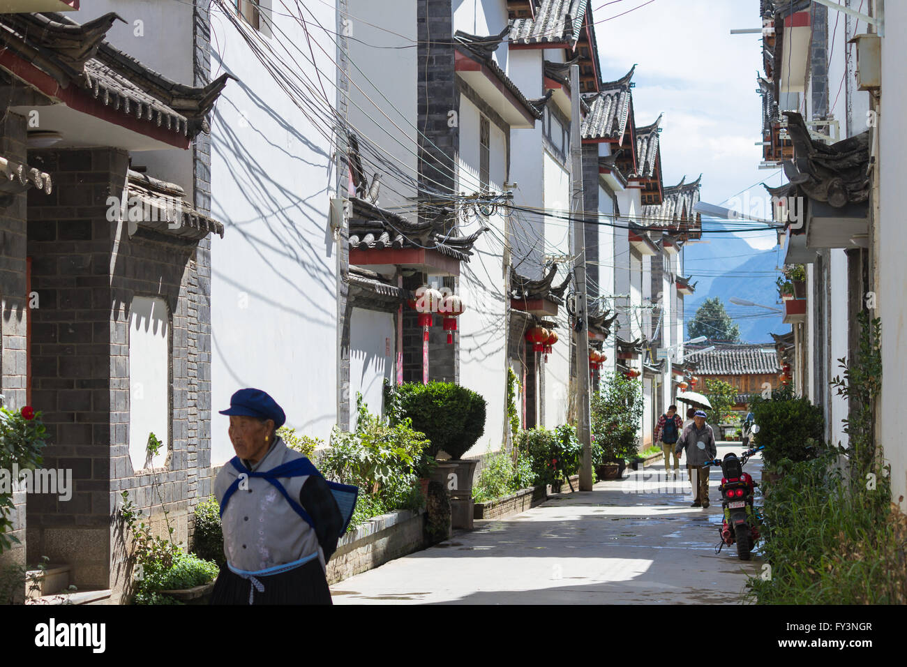 Die Menschen gehen über eine Straße inmitten chinesischer traditioneller Architektur in Shuhe, Lijiang alte Stadt in der Provinz Yunnan, China Stockfoto