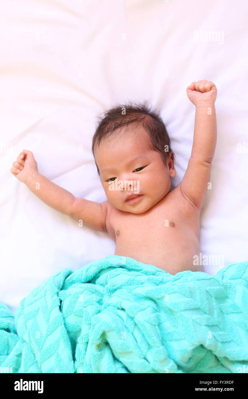 Neugeborenes Baby Asiens entspannen Sie sich in einer guten Stimmung auf weißen Bett und sah zufrieden, gute Gesundheit. Stockfoto