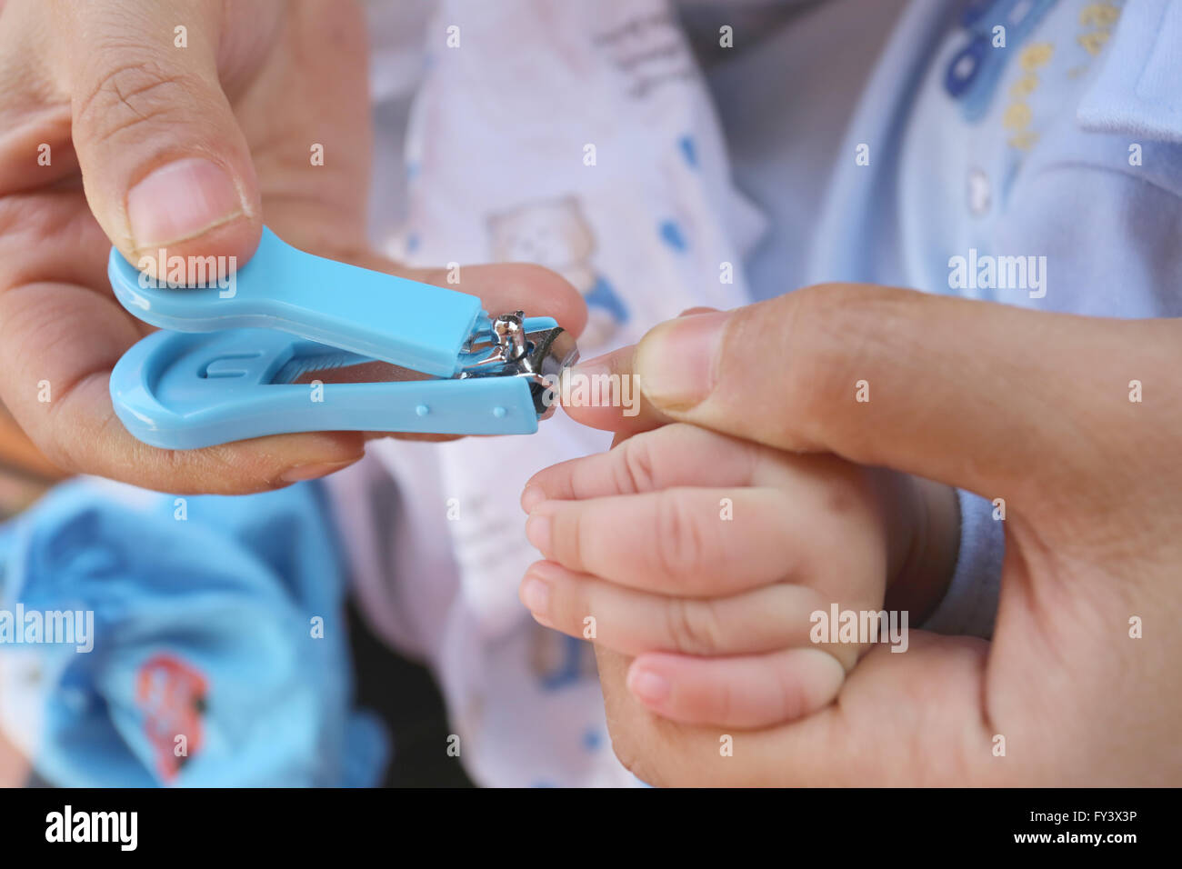 Blaue Nagelknipser, Fingernägel schneiden eines Kindes durch die Mutter. Stockfoto