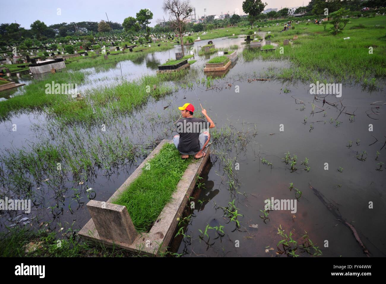 Jakarta, Indonesien. 21. April 2016. Ein indonesischer Mann Fische auf einem überfluteten öffentlichen Friedhof in Jakarta, Indonesien, 21. April 2016. © Zulkarnain/Xinhua/Alamy Live-Nachrichten Stockfoto