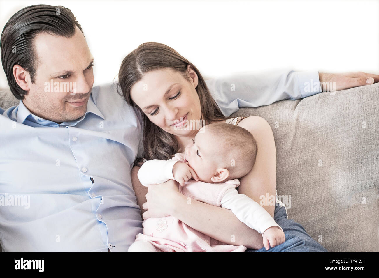 junge Familie mit einem kleinen Babymädchen auf der Couch sitzen Stockfoto